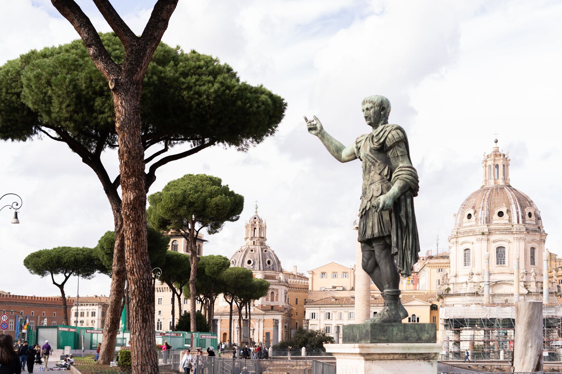 View of Julius Caesar statue with iconic Roman architecture in the background. — Julius Caesar The Man Who Changed Rome Forev