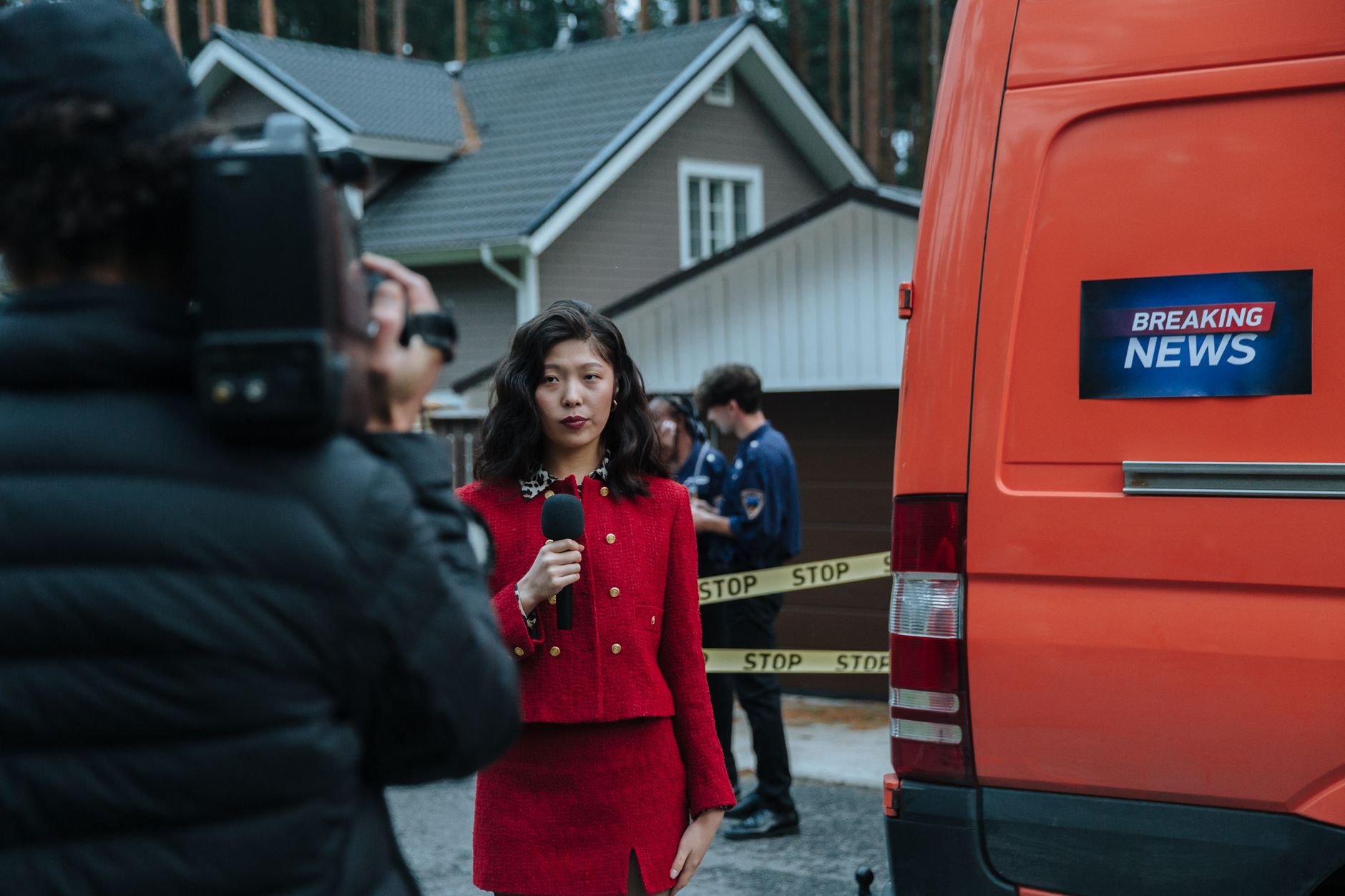 Female reporter in red with microphone reporting live at an outdoor crime scene with a news van. — Sensible Medical insurance