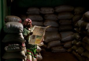 A man in traditional attire reads a newspaper in a dimly lit storeroom with stacked sacks. — Was unterscheidet Dracula Casino
