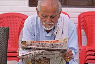 Elderly man engaging in daily reading of a newspaper while seated outdoors. — Wie steht Goldbet Casino im Test der Sicherheit