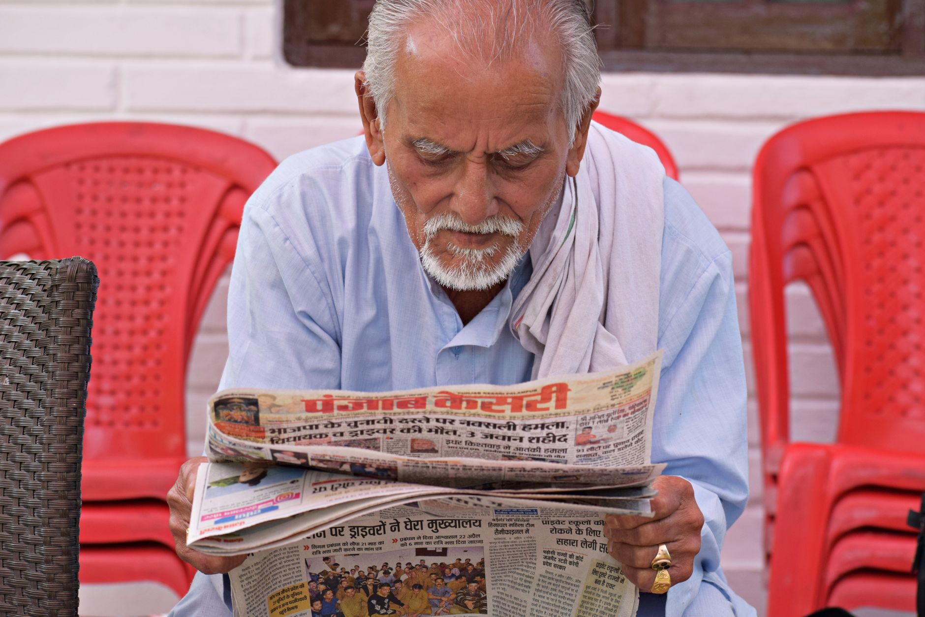 Elderly man engaging in daily reading of a newspaper while seated outdoors. — Wie steht Goldbet Casino im Test der Sicherheit